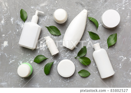 Organic cosmetic products with green leaves on cement background. Flat lay Organic cosmetic products with green leaves on cement background. Flat lay 83802527