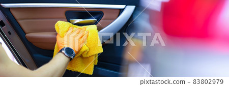 Male craftsman in gloves with microfiber wipes car handle of car closeup 83802979