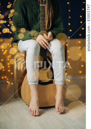 Legs of a teenager girl and a guitar in a home Legs of a teenager girl and a guitar in a home 83803747