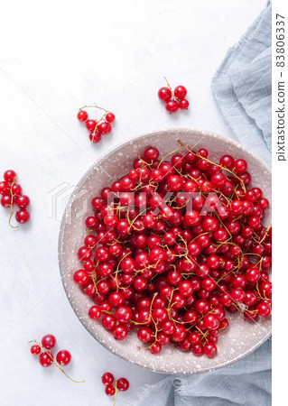 Fresh red currant in wooden bowl on grey table Fresh red currant in wooden bowl on grey table 83806337