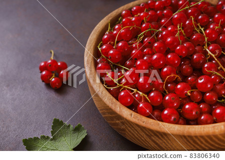 Fresh red currant in wooden bowl on dark table Fresh red currant in wooden bowl on dark table 83806340