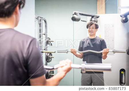 一個男人用槓鈴桿檢查表格(微笑) 一個男人用槓鈴桿檢查表格(微笑) 83807173