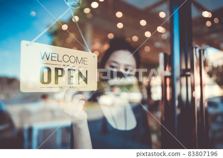 Barista or waitress woman wearing protective face mask and turning open sign board 83807196