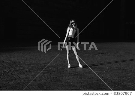 Contrasting black and white portrait of a woman with a skate in his hands. Contrasting black and white portrait of a woman with a skate in his hands. 83807907