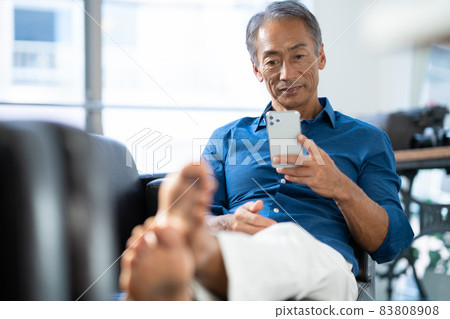 Middle man looking at a smartphone in the living room 83808908