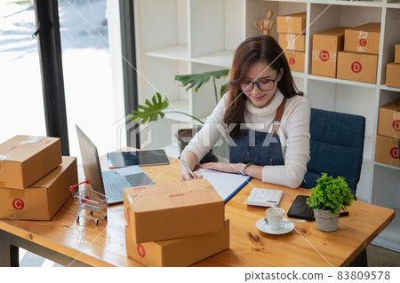 Starting Small business entrepreneur SME freelance,Portrait young woman working at home office, BOX,smartphone,laptop, online, marketing, packaging, delivery, SME, e-commerce concept. 83809578