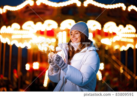 happy cheerful caucasian adult girl burns sparklers by holiday illumination on new years eve  83809591