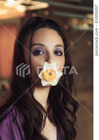 Art portrait of a woman with a flower in her teeth. 83809897