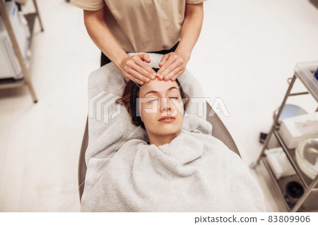Woman receiving facial massage in beauty salon. 83809906