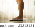young woman standing on digital weight scale 83812121