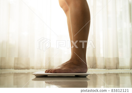 young woman standing on digital weight scale 83812121