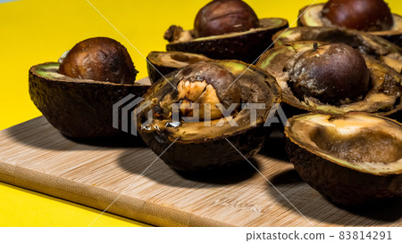Bad Avocado Halfs on Yellow background. Bad Vegan food. Rotten Avocado on wood Chipper next fork and knife. Necomestibile Food. Stop wasting food. Overripe Fruits Concept cannot be eaten. Copy space. 83814291