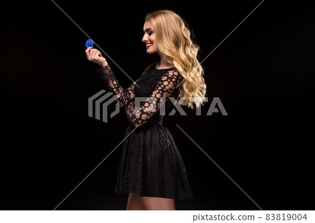 Beautiful blonde in a black dress with casino chips in hands isolated on a black background Beautiful blonde in a black dress with casino chips in hands isolated on a black background 83819004
