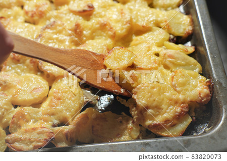 baked potatoes with cheese on a baking sheet. fresh potato gratin for family dinner. vegetarian food for holiday celebration. close up view. 83820073