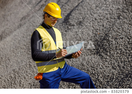 Male worker writing documents outdoors at cement factory Male worker writing documents outdoors at cement factory 83820379