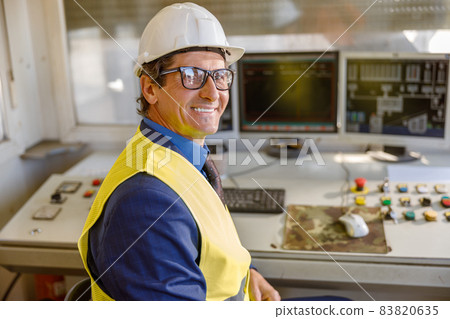 Cheerful male operator sitting at the table at factory Cheerful male operator sitting at the table at factory 83820635