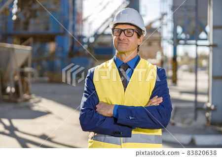 Joyful man engineer standing outdoors at factory Joyful man engineer standing outdoors at factory 83820638
