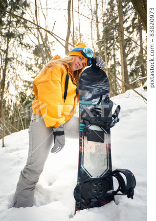 young girl or woman snowboarder goes in for winter sports in snowy forest she stands in snow and holds a snowboard young girl or woman snowboarder goes in for winter sports in snowy forest she stands in snow and holds a snowboard 83820973