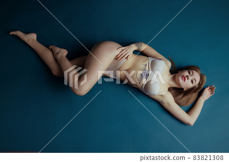 High angle view of young adorable red-headed girl in nude color underwear lying on floor isolated over old navy background. Natural beauty concept. High angle view of young adorable red-headed girl in nude color underwear lying on floor isolated over old navy background. Natural beauty concept. 83821308