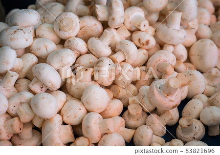 A close-up of champignons. Top view of a shelf with mushrooms in the market. 83821696
