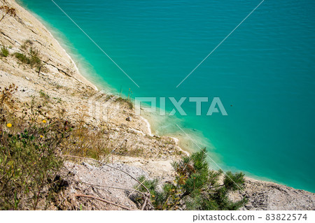 Unusual lake with turquoise water in the crater. Rocky stony shore chalk quarry in Belarus. Sunny summer day. 83822574