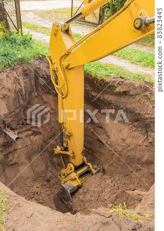 Hydraulic excavator piston digs deep pit in industrial area on construction site Hydraulic excavator piston digs deep pit in industrial area on construction site 83823445