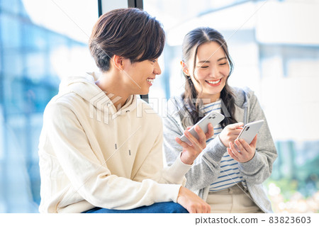 看著智能手機拍攝合作“LINK FOREST”的年輕大學生男女 83823603