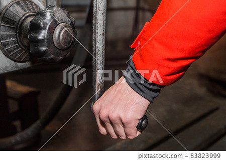The hand of a working man holds the handle and controls the work of the milling machine The hand of a working man holds the handle and controls the work of the milling machine 83823999