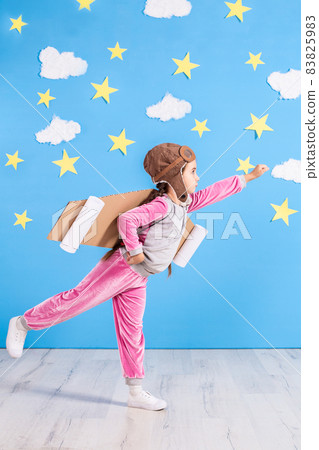 Girl pilot playing with toy jet pack at home. Success and leader concept Girl pilot playing with toy jet pack at home. Success and leader concept 83825983