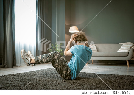 Athletic Man Does Sit-ups on the Carpet in His Apartment. A Strong Man Does Cardio At His Light Flat. Medium Close-up 83826542