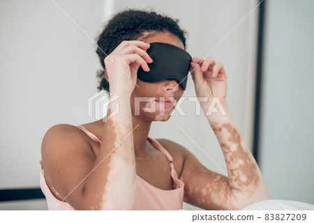 A young woman putting on a sleeping mask A young woman putting on a sleeping mask 83827209