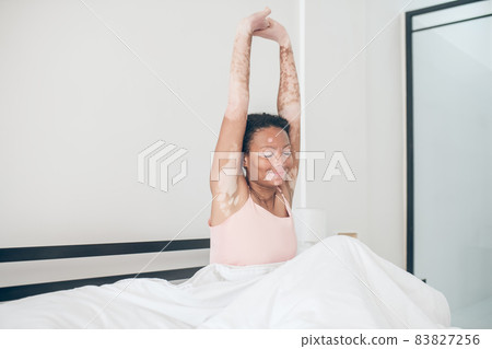 A cute young mulatte sitting in bed and looking relaxed 83827256