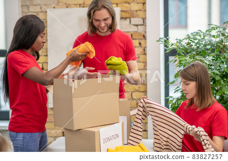 Volunteers in red thsirts taking part if donations distribution Volunteers in red thsirts taking part if donations distribution 83827257