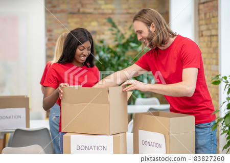 Volunteers in red thsirts taking part if donations distribution Volunteers in red thsirts taking part if donations distribution 83827260