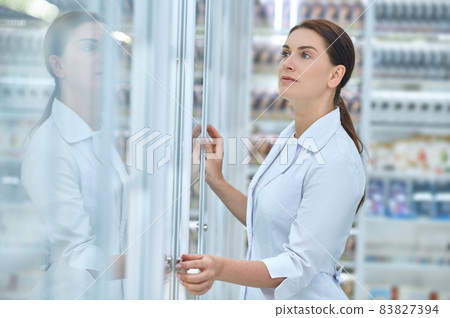Woman looking closely at pharmacy shelves 83827394