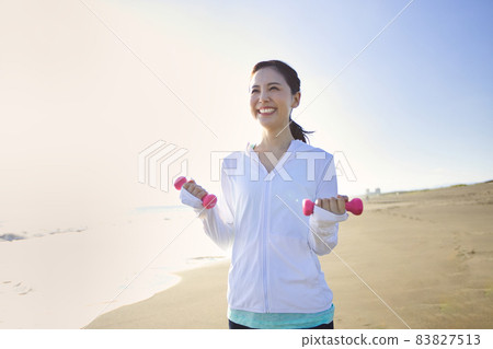 A young woman in sportswear walking on a sandy beach A young woman in sportswear walking on a sandy beach 83827513