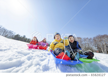 Children playing sledging in a snowy park 83828127