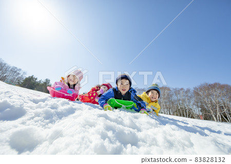 Children playing sledging in a snowy park 83828132