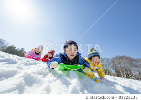Children playing sledging in a snowy park 83828133