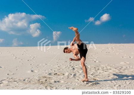 Portrait of young parkour man doing flip or somersault on the sand. Portrait of young parkour man doing flip or somersault on the sand. 83829100