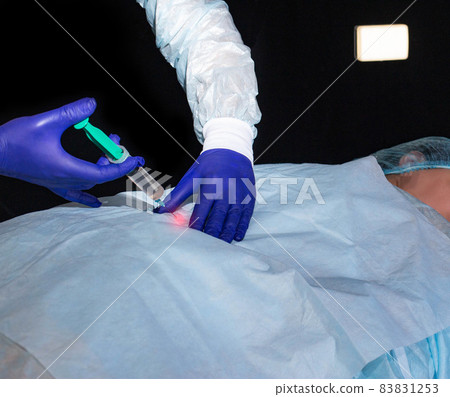 Doctor neurologist makes a therapeutic injection of medicine into the patient's hip joint. Treatment of arthrosis and joint inflammation Doctor neurologist makes a therapeutic injection of medicine into the patient's hip joint. Treatment of arthrosis and joint inflammation 83831253