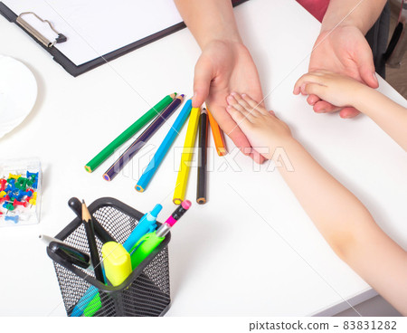 Hands of an adult and a child on the table with multi-colored pencils. The concept of psychological assistance to children, the development of stress resistance Hands of an adult and a child on the table with multi-colored pencils. The concept of psychological assistance to children, the development of stress resistance 83831282