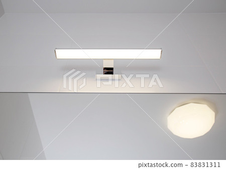 Stylish LED wall light above the bathroom mirror. Modern lighting, close-up 83831311