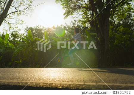 silhouette asian woman ride bicycle under tree in springtime silhouette asian woman ride bicycle under tree in springtime 83831792