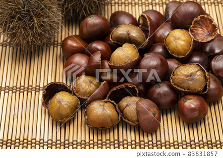 Sweet chestnuts with many shells placed on a bamboo mat 83831857