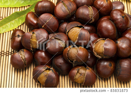 Sweet chestnuts with many shells placed on a bamboo mat 83831873