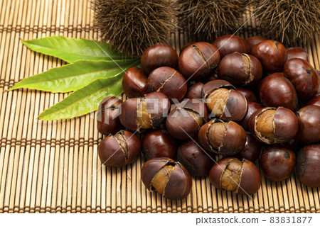 Sweet chestnuts with many shells placed on a bamboo mat 83831877