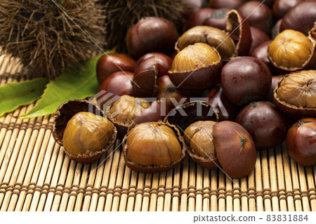 Sweet chestnuts with many shells placed on a bamboo mat 83831884