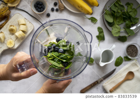 Cooking, preparring green spinach, banana and blueberry smoothie. Female hands, top view. Step by step recipe. Cooking, preparring green spinach, banana and blueberry smoothie. Female hands, top view. Step by step recipe. 83833539