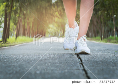 Female exercise walking on street in the park with close up on walking shoes. 83837532